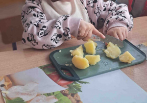 Dzieci kroją na deseczkach warzywa na sałatki