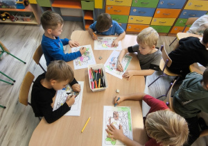 Dzieci kolorują przy stoliku.