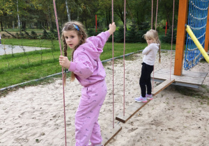 Dzieci idą po równoważni z desek zawieszonej nad ziemią
