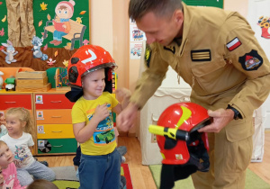 Chłopiec w żółtej koszulce zakłada kask.