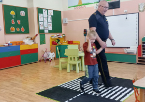 Strażnik przeprowadza chłopca przez symulator przejścia dla pieszych.