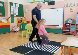 Mężczyzna przeprowadza dziewczynkę przez przejście dla pieszych.