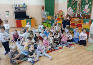 Przedszkolaki wykonują sobie pamiątkowe zdjęcie z gościem.