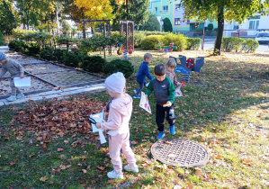 Przedszkolaki szukają liści z karty pracy.