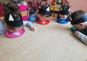 Dzieci piją mleko z miseczek za pomocą języczków