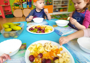 Dzieci wybierają swoje ulubione owoce do skomponowania swojej sałatki owocowej