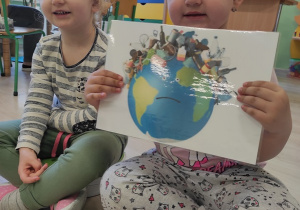Dziewczynki pokazują ilustrację "smutnej" i zanieczyszczonej Ziemi.