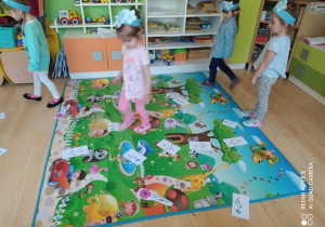 Dzieci chodzą po dywanie omijając kwiatki