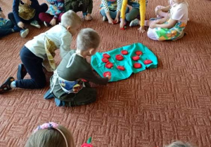 Dzieci na dywanie tworzą zbiór z filcowych jabłek