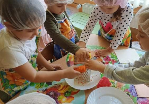 Dzieci przy stolikach ścierają na tarce marchewkę