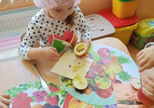 Dziewczynka przy stoliku wydrąża jabłko