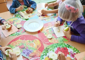 Dzieci przy stoliku wydrążają jabłka