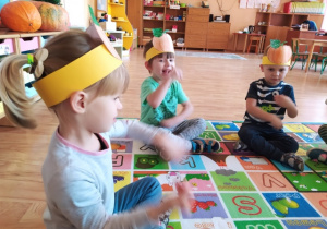 Dzieci siedzą na dywanie i ilustrują treść wierszyka ruchem oraz gestem