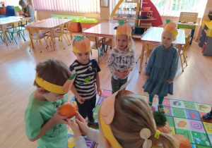 Dzieci stojąc kole uczestniczą w zabawie "Podaj dynię"