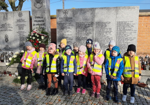 Dzieci z grupy I stoją przy pomniku poległych żołnierzy.