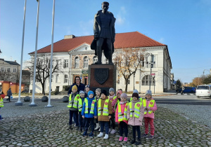 Dzieci z grupy I wraz z Panią stoją przy pomniku Józefa Piłsudskiego.