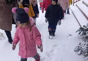 dzieci bawią się w ogrodzie przedszkolnym na śniegu