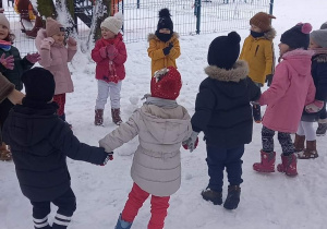 dzieci bawią się w ogrodzie przedszkolnym na śniegu