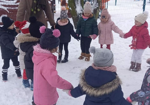 dzieci bawią się w ogrodzie przedszkolnym na śniegu