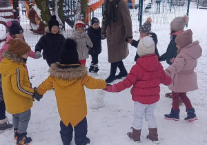 dzieci bawią się w ogrodzie przedszkolnym na śniegu